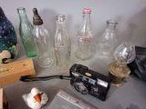 many glass bottles and a camera sitting on a table