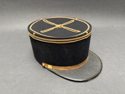 chapeau noir orné d'une bordure dorée et d'un motif représentant deux os croisés sur le dessus