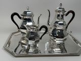 two silver teapots on a silver tray on a white table