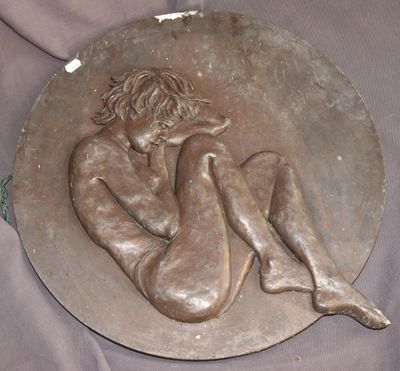 une plaque en bronze représentant une femme assise sur un plateau