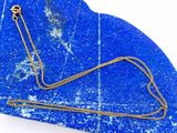 collier posé sur une plaque de marbre bleu, avec une chaîne en or
