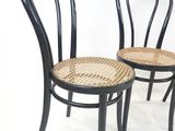 deux chaises noires avec une assise en osier, sur fond blanc