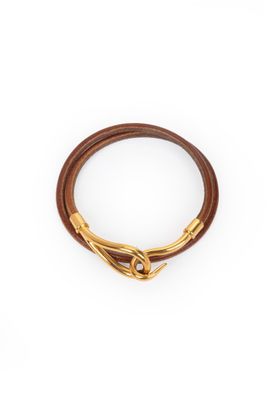 un gros plan sur un bracelet en cuir marron muni d'un fermoir doré