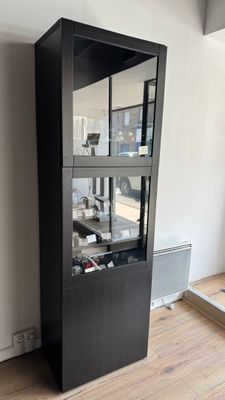 a black cabinet with a glass door in the corner of a room