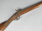 un vieux pistolet avec une poignée en bois sur une surface blanche