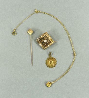 une photo d'un collier en or avec une broche et d'autres objets
