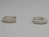 une paire de boucles d'oreilles créoles en diamant posées sur une surface blanche