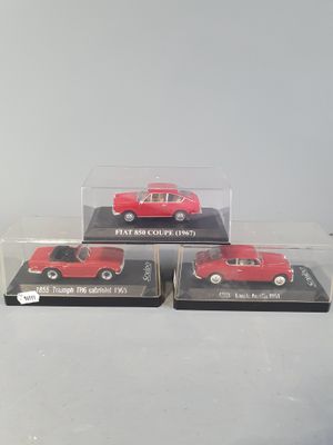 three red die cast cars in clear boxes on a white surface