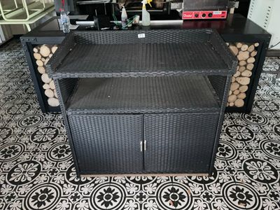 une photo d'un banc en osier noir sur lequel sont empilées des bûches