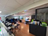 une salle où se trouvent de nombreux bureaux et chaises