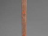 an old wooden pole with carvings on it and a bird perched on top
