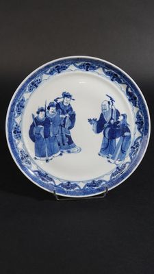 deux assiettes bleues et blanches ornées de personnages, posées sur une table