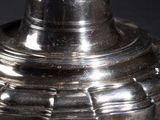 a silver candle holder with a candle on top of it