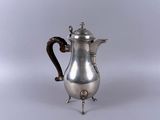 une cafetière ancienne en argent posée sur un support, sur fond blanc