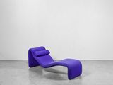 une chaise longue violette dans une pièce blanche