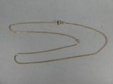 gros plan d'un collier en or avec une chaîne sur une surface blanche