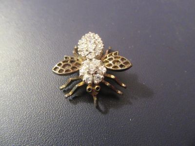 une broche en forme d'abeille en or et diamants sur un fond noir