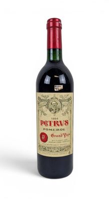 the bottle of red wine is sitting on a white surface