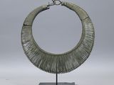une photo d'un collier en argent posé sur un socle noir