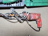 a corded drill and other tools sitting on a table