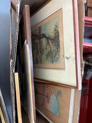 une pile d'œuvres d'art encadrées dans une boîte posée par terre