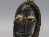 paire de masques africains en bois posés sur un socle, sur fond blanc
