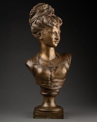 a bronze bust of a woman wearing a necklace