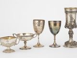 cinq gobelets en argent et deux tasses en argent sur fond blanc