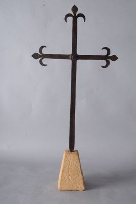 une croix en bois posée sur un socle, sur fond gris