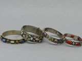 three silver rings with red and blue stones on them on a white surface