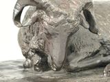 a statue of a ram laying down on the ground