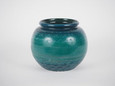 un vase bleu posé sur une surface blanche