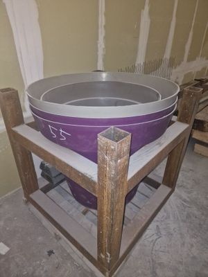 une grande casserole posée sur un support en bois dans une pièce