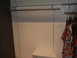 a closet with a shelf and clothes hanging on it