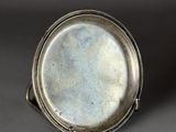 an old silver plate sitting on top of a gray surface
