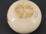 a white vase with a brown lid on a black table