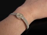 le poignet d'une femme portant une montre, sur fond noir