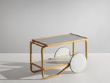 une petite charrette en bois à deux roues posée sur une surface blanche