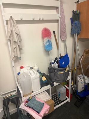 a room with a shelf and a rack with cleaning supplies on it
