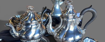 deux théières en argent et une assiette en argent posées sur une table