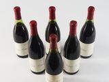 six bottles of wine are lined up in a row on a white surface