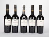 quatre bouteilles de vin sont alignées sur une surface blanche