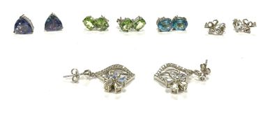 six pairs of earrings with different colored stones on a white surface