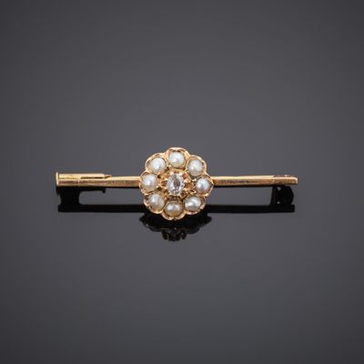 a close up of a gold and pearl hair clip on a black surface