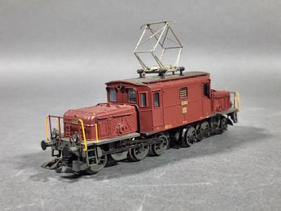 un train rouge sur les rails, sur un fond gris