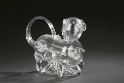 crystal figurine of a monkey holding a wine bottle on a black background