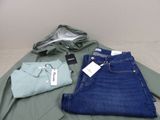 deux paires de jeans et une chemise posées sur un lit