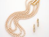a close up of a necklace and earring with pearls on a white surface