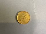 une pièce d'or sur laquelle est gravé un triangle, posée sur une table