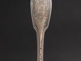 a silver spoon with an ornate design on it sitting on top of a table